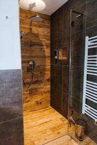 een badkamer met een douche en een houten muur bij Apartments Haufhof , Haus im Ennstal bei Schladming in Haus im Ennstal