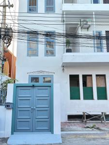a white building with a blue door in front of it at After-Grad Poshtel in Pattaya South