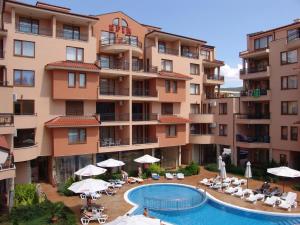an apartment building with a pool and chairs and umbrellas at Apart Hotel Efir in Sunny Beach
