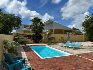 una piscina con due sedie blu e una casa di The Julianadorp Villas a Willemstad