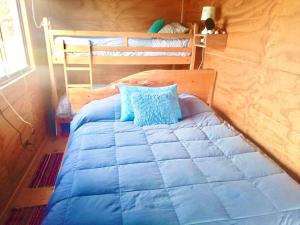 uma cama azul num quarto com 2 beliches em CASA PLAYA CHAICURA em Ancud
