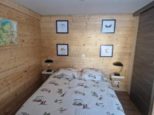 1 dormitorio con 1 cama en una pared de madera en La Duchère Le Plan La Giettaz en La Giettaz