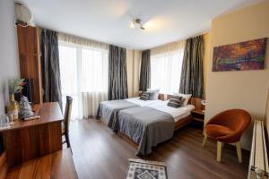 a hotel room with two beds and a desk at Ахат- къща за гости in Kyustendil