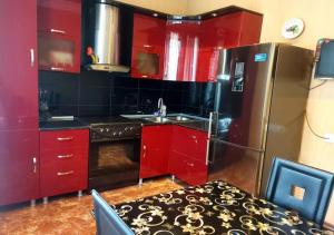 uma cozinha com armários vermelhos e um frigorífico de aço inoxidável em GOAL ApartmentS 2 em Tbilisi