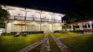 a large white building with a balcony and benches at Weleges Place in Hikkaduwa