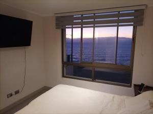 1 dormitorio con cama y ventana grande en Departamento Antofagasta. Playa privada, en La Chimba