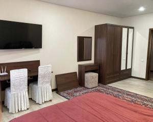 una camera con letto, scrivania e TV di BAQDOS Guest House a Shchuchinsk