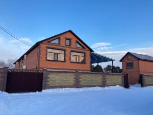 una casa di mattoni con una recinzione nella neve di BAQDOS Guest House a Shchuchinsk