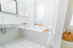 une salle de bain blanche avec une baignoire et un lavabo dans l'établissement Hansekoje direkt an der Hafenspitze, à Flensbourg 10 autres photos