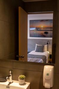 uma casa de banho com um espelho, uma cama e um lavatório. em TAS D VIAJE Suites - Hostel Boutique em Punta del Este