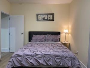 a bedroom with a large bed with a purple comforter at Luxury Suite with King Bed-4 minutes to The Falls in Niagara Falls