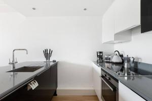 a kitchen with black and white counters and a sink at Stylish apartment with underground parking in London