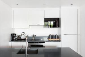 a white kitchen with a sink and a stove at Stylish apartment with underground parking in London