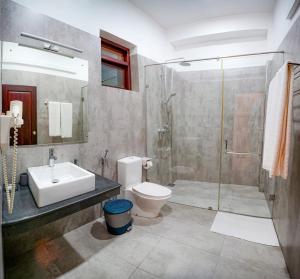 un bagno con lavandino, wc e doccia di Weleges Place a Hikkaduwa