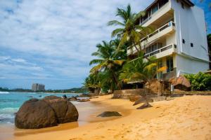 a hotel on a beach with rocks in the sand at La Veranda Di Serena in Unawatuna