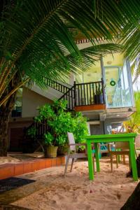 a green table and a bench in front of a house at La Veranda Di Serena in Unawatuna