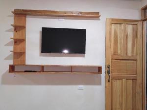 a flat screen tv on a wall with a wooden shelf at Papaturro House in La Cruz