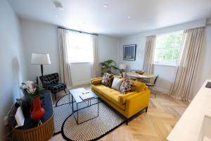 a living room with a yellow couch and a table at Modern newly refurbished 2nd floor stylish flat in Fitzrovia in London