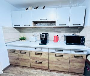a kitchen with white cabinets and a microwave at Cabana Harghita Băi in Harghita-Băi