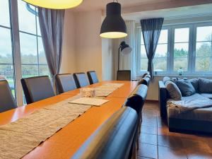 ein Esszimmer mit einem langen Tisch und einem Sofa in der Unterkunft Charmantes Ferienhaus an der Mosel in Ediger-Eller