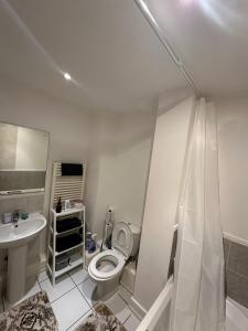 Baño blanco con aseo y lavamanos en Cozzy Stay, en Londres