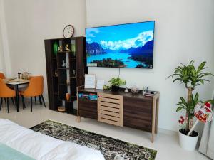 Damac Hills Cozy Studio Apartment في دبي: غرفة معيشة مع تلفزيون بشاشة مسطحة على جدار
