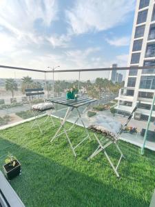 Damac Hills Cozy Studio Apartment في دبي: شرفة مع طاولة وكراسي على العشب