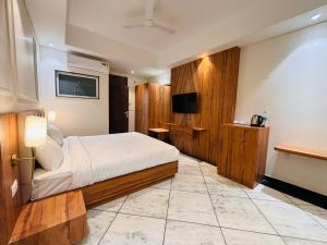 Hotel Saaj Mansion في جايبور: غرفة فندق بسرير وتلفزيون