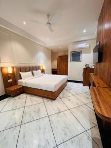 Hotel Saaj Mansion في جايبور: غرفة نوم بسرير وتلفزيون على جدار