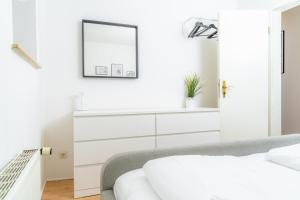 - une chambre blanche avec un lit blanc et un miroir dans l'établissement Smutjes Koje, mittendrin und doch am Meer, à Flensbourg