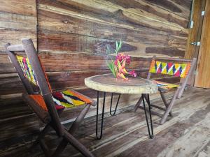 una mesa y dos sillas con un jarrón de flores en Natyva House en Guachaca