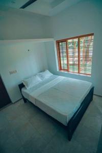 1 dormitorio con 1 cama en una habitación con ventana en Paddy N Pond Tree house Villa 2R, en Angamaly