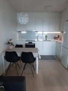 uma cozinha branca com uma mesa e cadeiras em Upea kaksio Näsijärven rannalla em Tampere