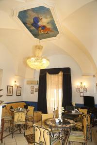 una sala de estar con mesas, sillas y una lámpara de araña. en Nuovo Hotel Sangiuliano, en Catania