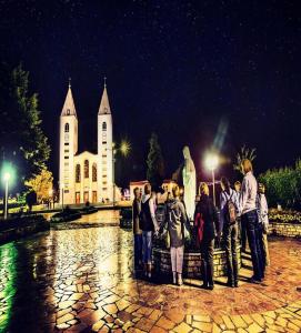 un groupe de personnes debout devant une église dans l'établissement Mica Medjugorje, à Međugorje