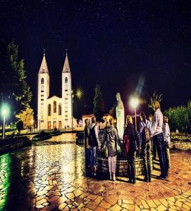 a group of people standing in front of a church at Mica Medjugorje in Međugorje