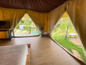 a tent with a bed and a view of a yard at khaokho keree tara in Khao Kho