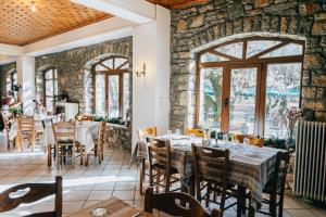 a dining room with tables and chairs and a stone wall at Mountain Hotels "Aroanides" in Planitéron