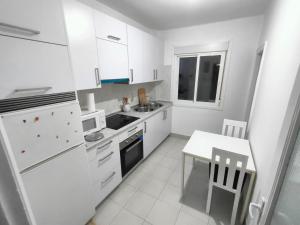 a kitchen with white appliances and a white table and chairs at Vintage House in Vigo +2 photos