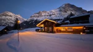 una casa en la nieve frente a una montaña en Jägerstübli Grindelwald, en Grindelwald