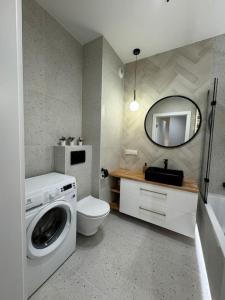 uma casa de banho com uma máquina de lavar roupa e um espelho. em Forest Apart IV em Varsóvia