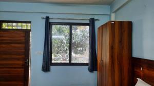 ein Fenster in einem blauen Zimmer mit einer Holztür in der Unterkunft Crescent Moon Homestay in Rishikesh