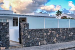 a white house with a stone wall at Mar Azul Puerto Calero in Puerto Calero