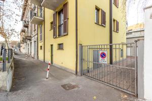 een hek voor een geel gebouw zonder parkeerbord bij Station & Center - Self Check-in & Access in Como