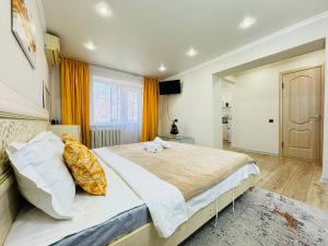 a large bedroom with a large bed with yellow curtains at Infinity Estate MEGA Park in Almaty