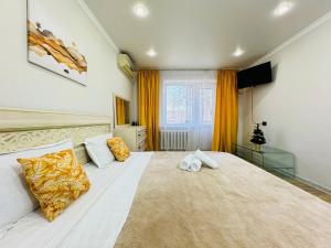 a bedroom with a large white bed with yellow curtains at Infinity Estate MEGA Park in Almaty