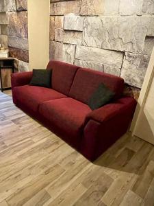 a red couch sitting in front of a stone wall at Casa del castorino in Abbadia San Salvatore