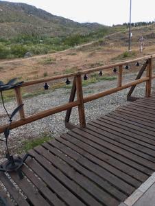 una barandilla de madera en un puente con una colina al fondo en Cabañas y Tinajas FERISI, en Cochrane