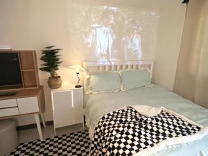 um pequeno quarto com uma cama e uma televisão em white room private bathroom Red Panda Guesthouse em Seul