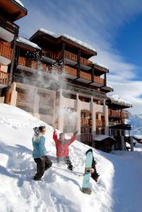 zwei Personen stehen im Schnee vor einer Lodge in der Unterkunft Résidence Odalys La Licorne in La Plagne